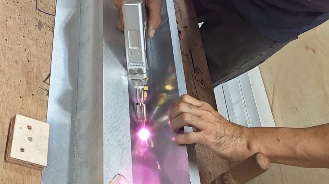 Laser Welding Stainless Steel and Aluminium: Low-Distortion Seams for Finish-Critical Work Handheld fibre laser welding along an aluminium channel section, with the beam visible at the joint.