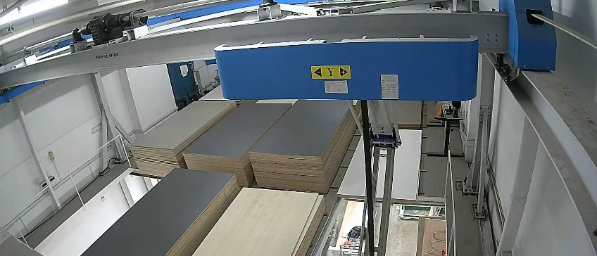 Beyond Emission Grades: Choosing Plywood That Survives Singapore's Humidity An automated panel storage system, with sheet material held flat in stacks under an overhead gantry lifter and the cutting line running beneath.