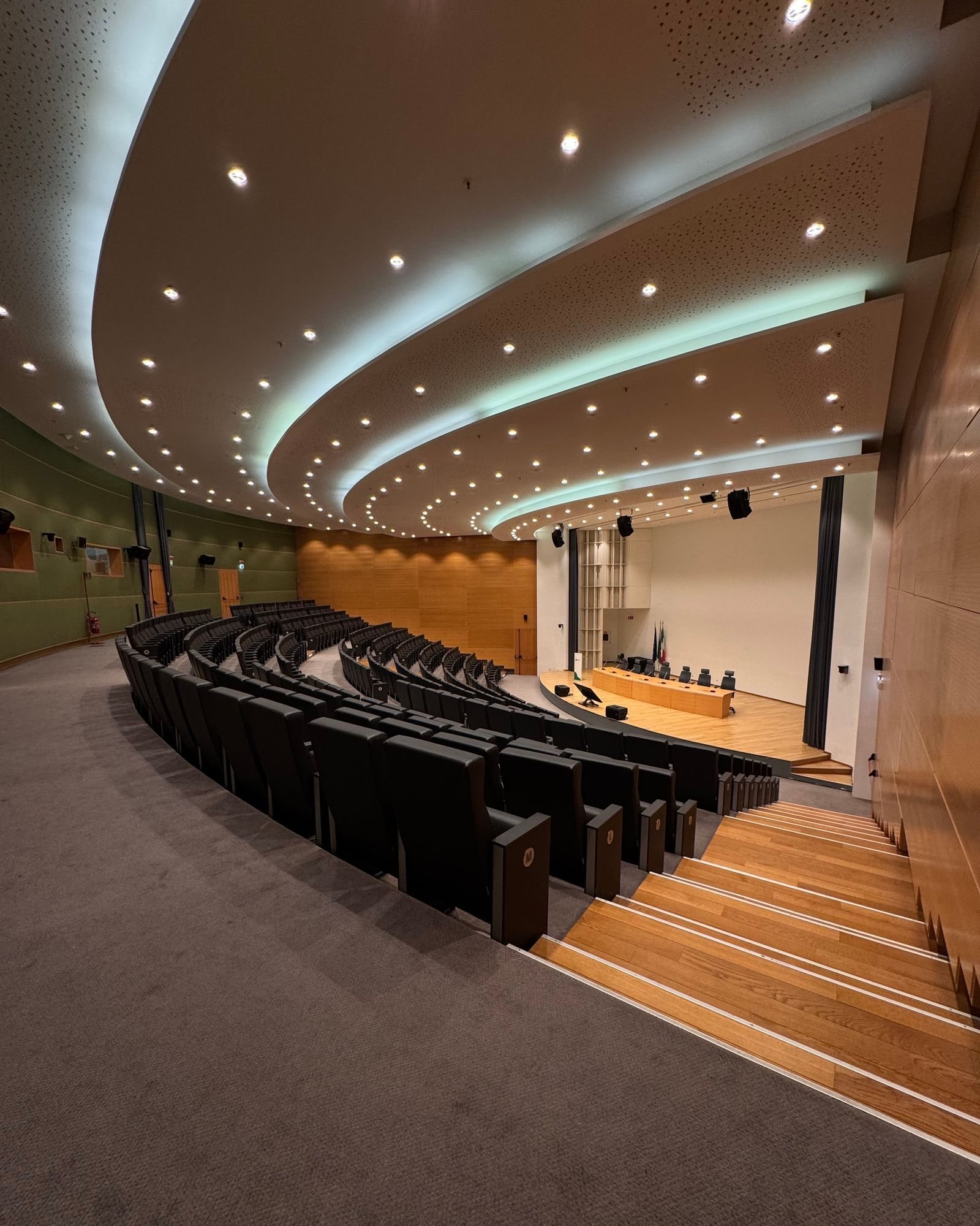 Acoustic Panels for Theatres and Auditoriums in Singapore: What the Installation Has to Get Right Auditorium with curved raked seating, timber stair and a curved perforated ceiling above